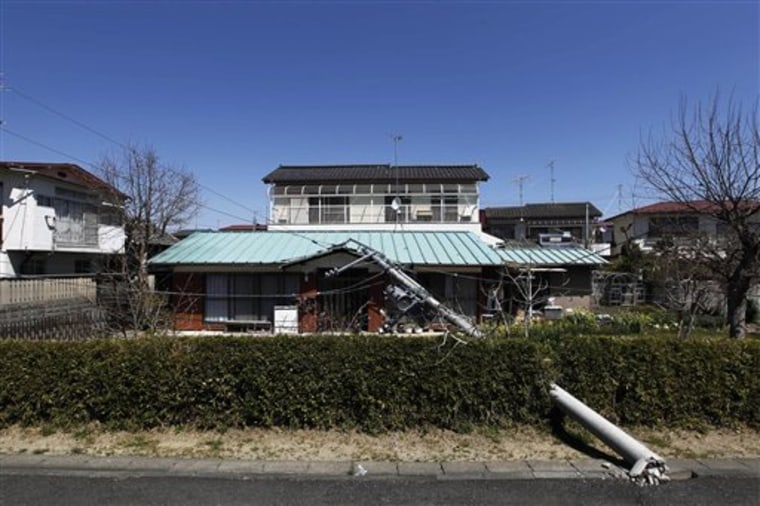 In this photo taken Sunday, April 17, 2011, a downed electrical pole lies on a house in Futaba, Fukushima Prefecture, northeastern Japan. Having survived the March 11, 2011 earthquake and tsunami, most of Futaba was intact, but thousands had to evacuate the city in the wake of the radiation warnings from the neighboring Fukushima Dai-ichi Nuclear power station. (AP Photo/Hiro Komae)